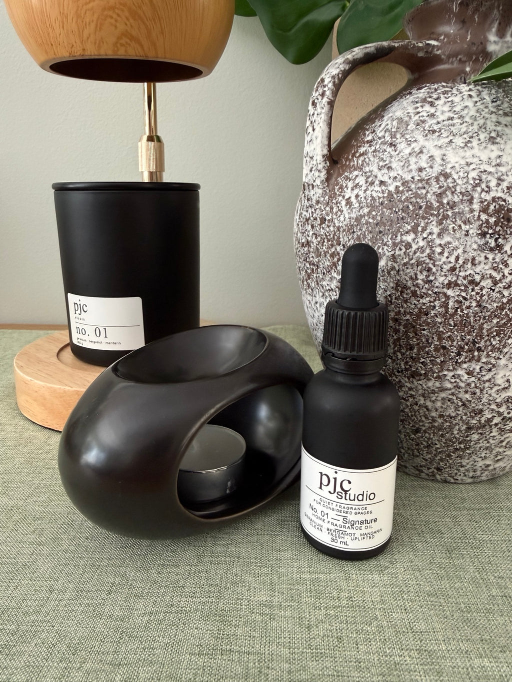 No. 01 Signature candle styled at home beside an oil burner and fragrance oil, sold separately.